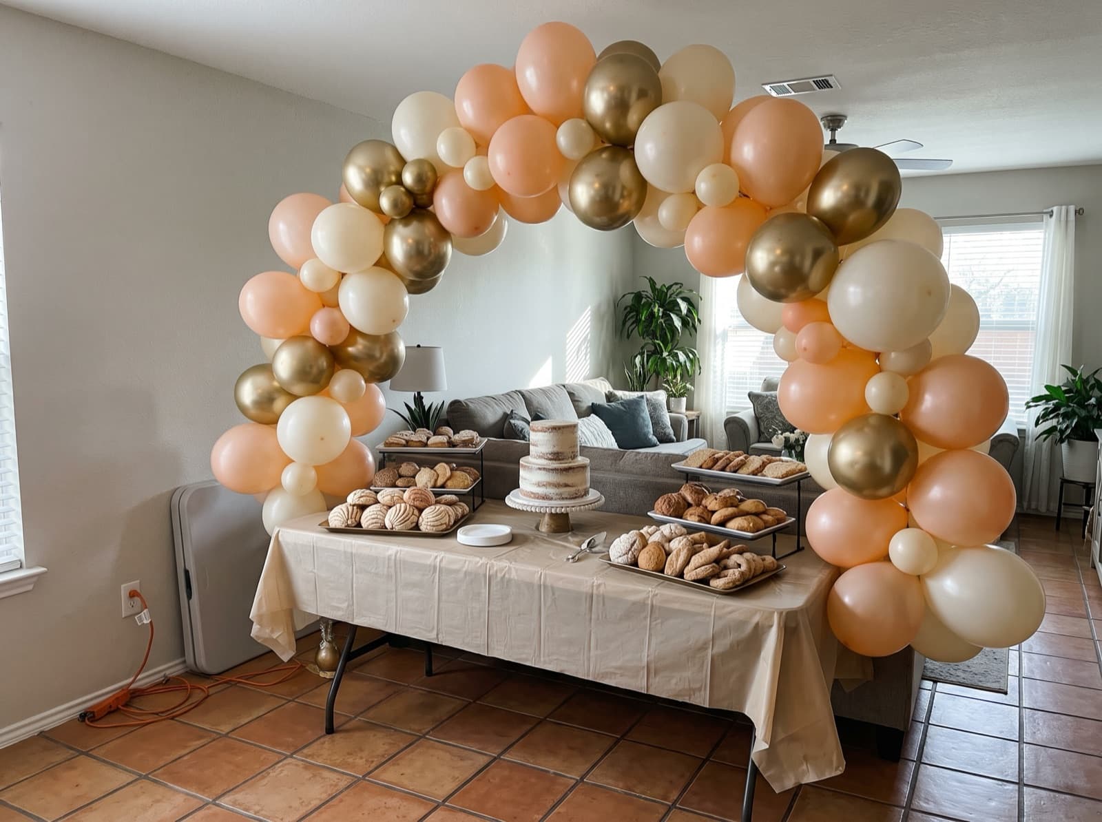 Organic balloon arch in peach, ivory and chrome gold over a dessert table