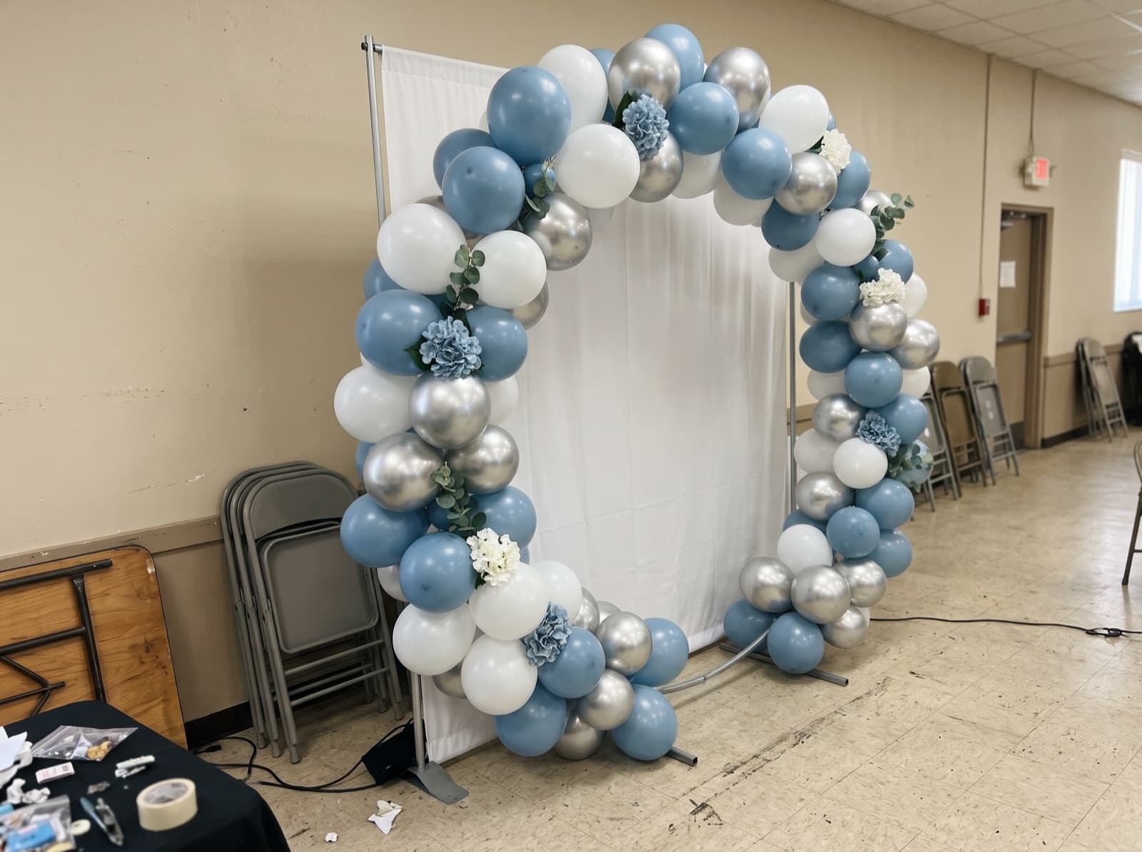 Round balloon arch in dusty blue and white framing a photo corner