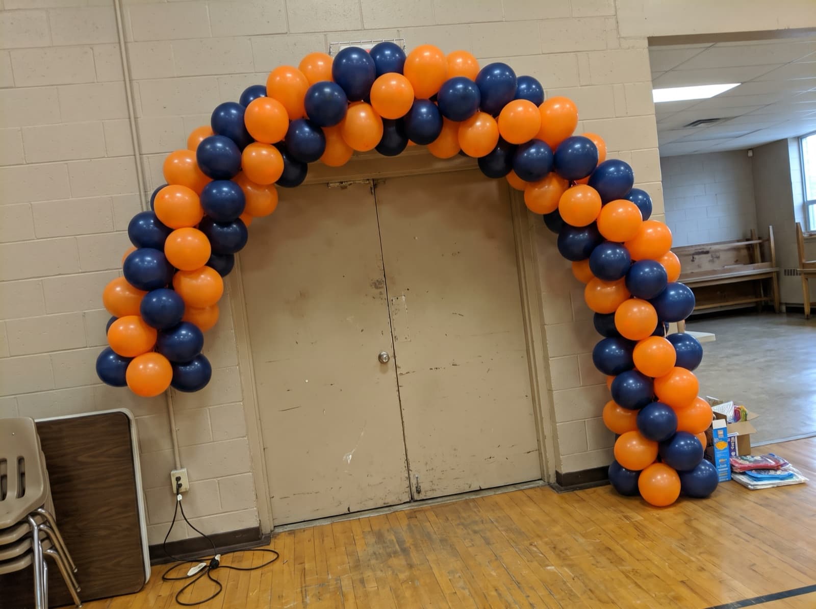 Spiral balloon arch in school colors over a gym entrance